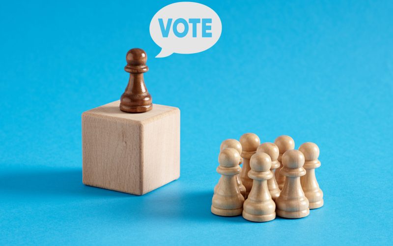 Leader chess pawn at the rostrum gives the message of Vote to the crowd of audience. Leader chess pawn at the rostrum gives the message of Vote to the crowd of audience.