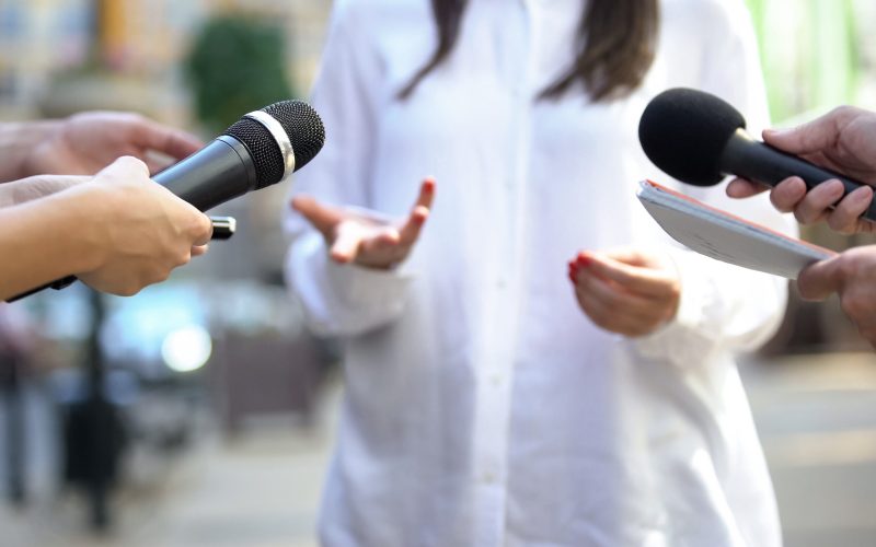 Female politician talking on media press conference, public relations, event